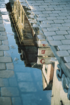 Spiegelung der Hausfassaden in einer Regenpfütze